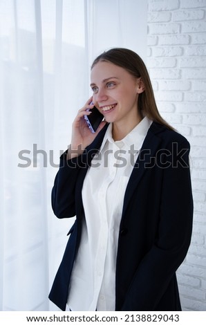 a businesswoman is talking on phone near the window. business meeting. talking to colleagues on phone. vertical photo