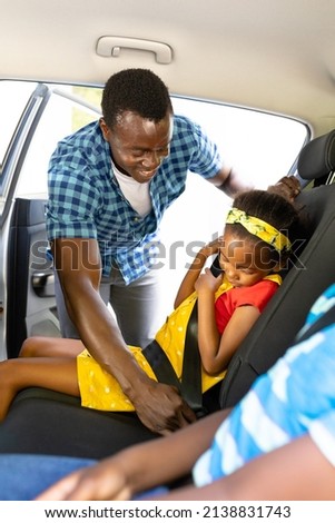 Smiling african american father teaching daughter to adjust seat belt while sitting in car. unaltered, family, childhood, safety, learning, weekend and travel concept. Royalty-Free Stock Photo #2138831743