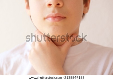 close-up of hands of child holds throat, boy of 10 years old is sick, concept of children's health, pediatrics, thyroid inflammation, Overview of the Thyroid Gland, loss of voice Royalty-Free Stock Photo #2138849153