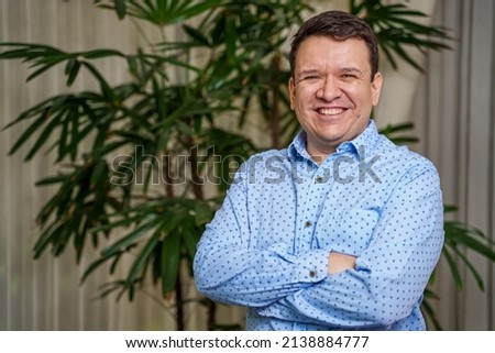 Smiling young man in living room with house plant in background