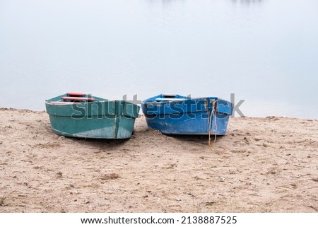 Two old boats on the sandy shore. Two small wooden boats on the sand near the pond. Royalty-Free Stock Photo #2138887525