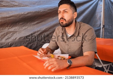 Young man enjoying tacos outside on a table