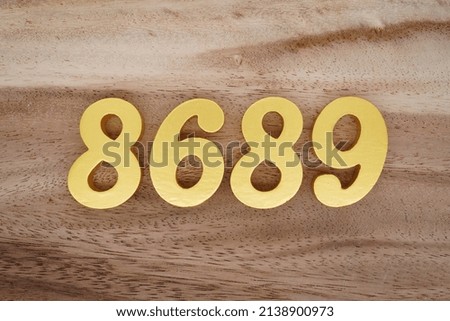 Wooden  numerals 8689 painted in gold on a dark brown and white patterned plank background.