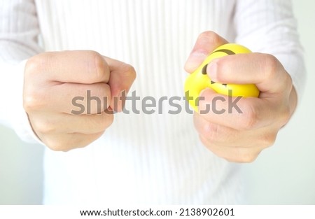 Hands of man with a gentle personality He exhibits stressful behavior from work, and he squeezes the yellow ball expressing emotion, anger, displeasure. Medical concepts and emotional regulation Royalty-Free Stock Photo #2138902601