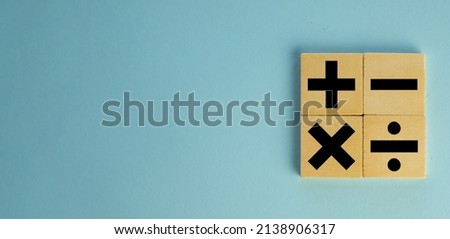 mathematic concept.,Black color of mathematical operations or Plus, minus, multiply, divide symbols on wooden cube over blue pastel background with copyspace for put text or logo.