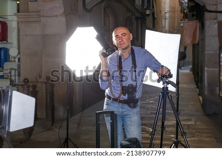 Portrait of adult photographer with his camera during professional photo shooting on town street
