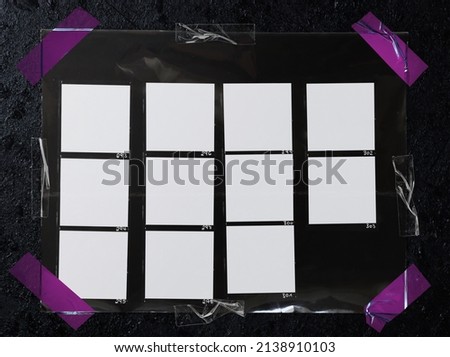 top shot photo of black and white hand copy contact sheet with 11 empty frames fixed by pink sticker tape on black graphite background. cool retro picture placeholder.