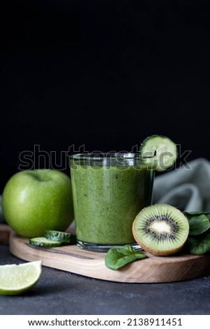 Green detox smoothie in a glass on a dark background, copy space. Green smoothie of spinach, kiwi and lime in a glass 