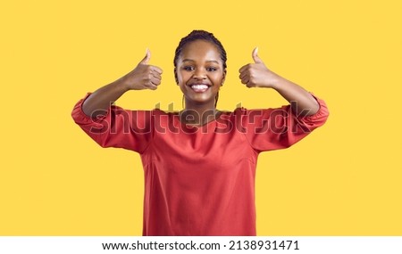 Portrait of happy young African American woman isolated on yellow studio background show thumb up give recommendation. Smiling black female client recommend good quality service. Royalty-Free Stock Photo #2138931471