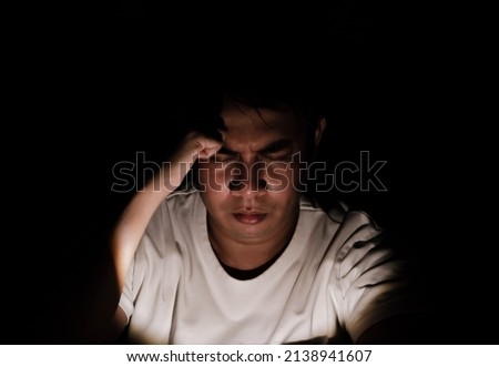 Asian miserable depressed man sitting alone in dark background. Depression and mental health concept. Royalty-Free Stock Photo #2138941607