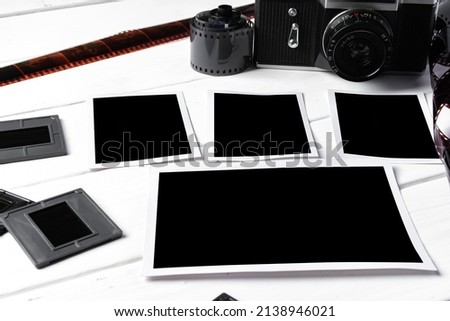 Old retro camera and photos on white wooden background, close up