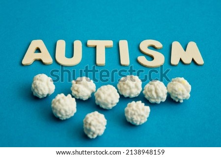 Isolated word Autism on blue background with some puffed candies. 