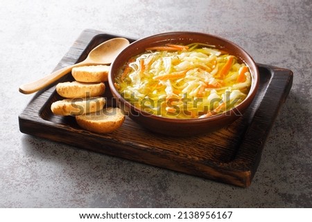 Healthy diet vegetable julienne soup served with toast close-up in a bowl on a wooden tray. Horizontal

