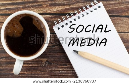 SOCIAL MEDIA text on a notebook with coffee on the wooden background