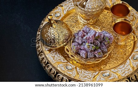 Still life with traditional luxury golden arabic coffee set with jezva, cup and turkish delights. Dark background. Ramadan concept.