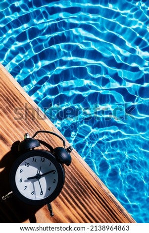 Wood board black alarm daily clock. Blue transparent reflect wave water surface ocean. Time aging running out. Vacation summer health care concept. Countdown youth. Flat lay, place for text. Vertical