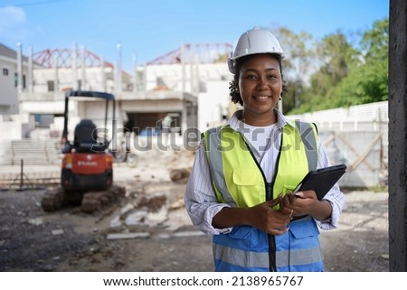 
Smiling female engineer, wearing a hard hat, vest, holding a tablet.cute woman with black skin.Working on construction sites, houses and buildings.Workers are smart.use of technology in industry Royalty-Free Stock Photo #2138965767