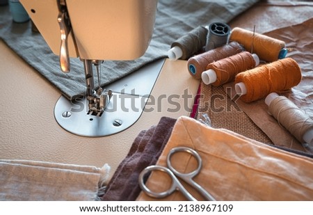 Sewing machine, thread, scissors and fabric close-up. Design workplace.