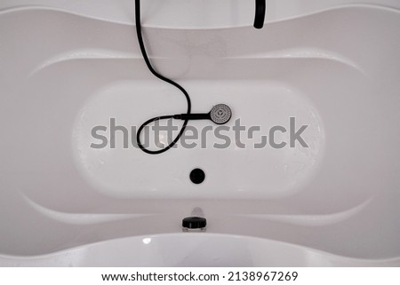 White acrylic bathtub with shower and faucet, top view. Bathroom and hygiene backgrounds and textures