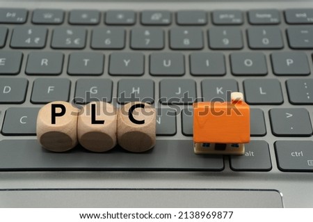 public limited company (PLC) is a public company in the United Kingdom.word is written on dice, next to house. Royalty-Free Stock Photo #2138969877