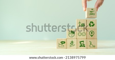 Net zero and carbon neutral concept. Net zero greenhouse gas emissions target. Climate neutral long term strategy.  Stacking wooden cubes with green net zero and save world icon on grey backgroud. Royalty-Free Stock Photo #2138975799