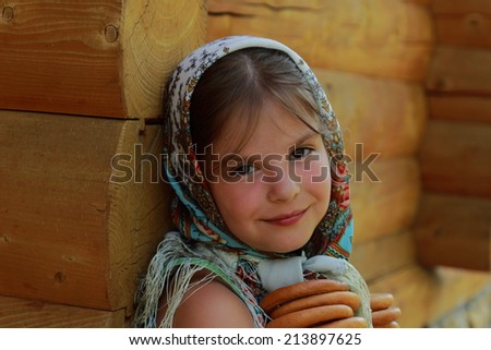 Outdoor image of beautiful russian little girl with traditional russian food wearing Pavloposadsky scarf