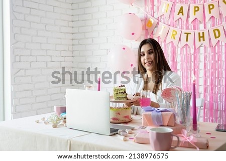 Birthday party. Birthday tables. Attractive brunette woman in white party clothes celebrating birthday using video call chatting with friends