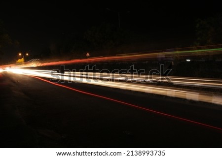 In night time at  highway road the car and other vehicles are passing with bright light took this picture in long exposure ,light painting