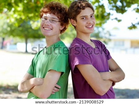 Weve got each others backs. Portrait of two boys standing back to back outdoors on a sunny day. Royalty-Free Stock Photo #2139008529