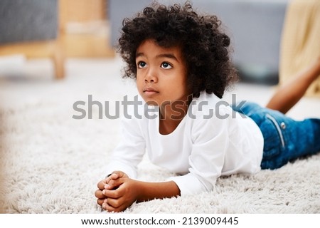I dont like to be disturbed when I watch cartoons. Cropped shot of an adorable little boy lying down on a carpet and watching tv at home.