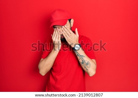 Hispanic man with beard wearing delivery uniform and cap rubbing eyes for fatigue and headache, sleepy and tired expression. vision problem 