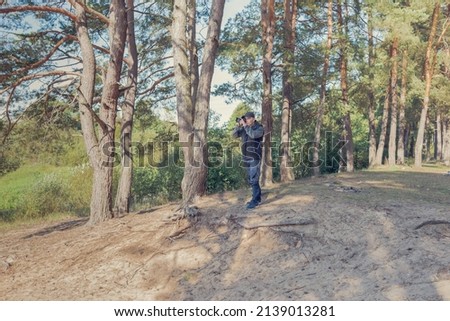 Man nature photographer taking pictures in the forest. 