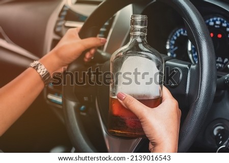Drunk female driver with alcohol bottles sitting behind the wheel, not drinking and driving. Royalty-Free Stock Photo #2139016543