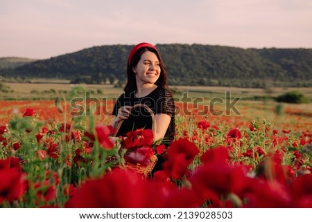 beautiful woman in black dress on sunset at the poppies flowers field