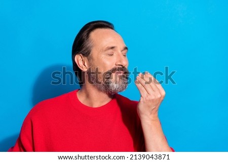 Portrait of good mood handsome male with closed eyes enjoying food wear red jumper isolated on blue color background