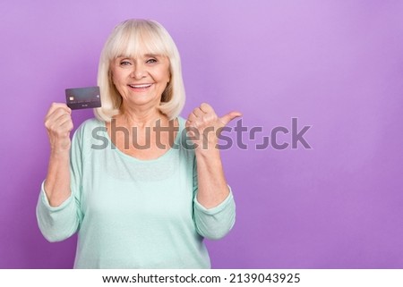 Photo of grandma hold debit card direct finger empty space loan option wear teal shirt isolated violet color background