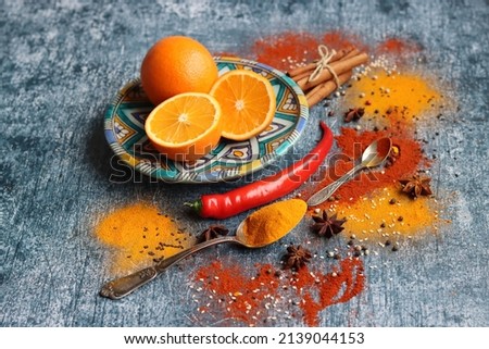 Vibrant still life with oranges and spices. Colorful image of aroma spices. Dark grey textured background with copy space. 