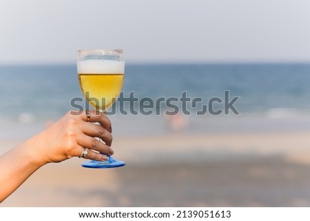 Woman holding a glass of beer on the beach