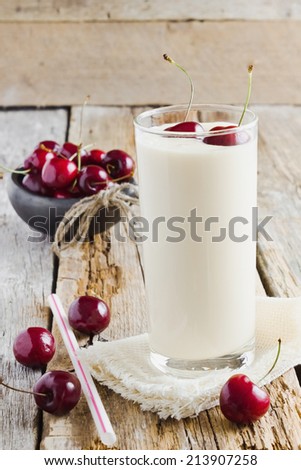fresh yogurt in a glass and ripe cherries on a wooden background. health and diet food