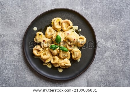 Tortellini ravioli creamy pasta. Italian ravioli pasta with pumpkin and basil on rustic background