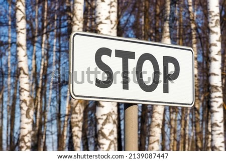 Stop road sign on road in birch forest. STOP