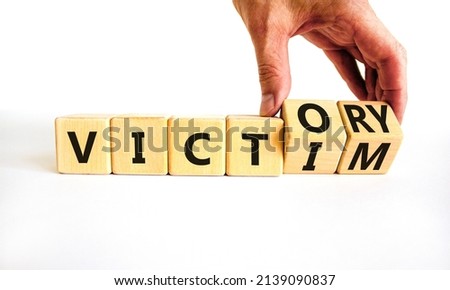 From victim to victory symbol. Businessman turns wooden cubes and changes concept words Victim to Victory. Beautiful white background. Business support from victim to victory concept. Copy space.