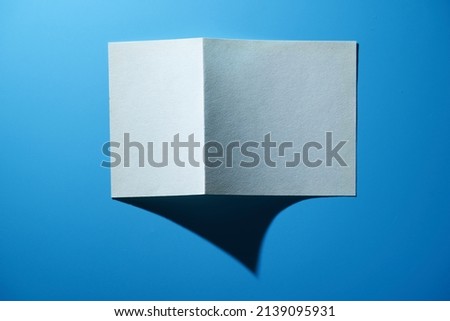 folded blank paper against blue background                       