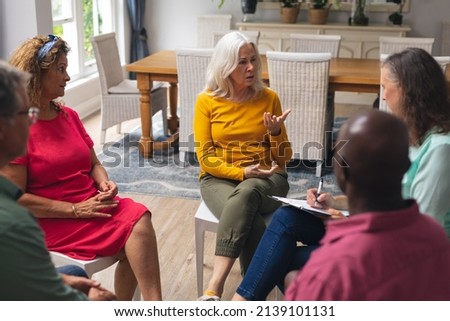 Caucasian senior woman talking with multiracial people at group therapy session. unaltered, support, alternative therapy, community outreach, mental wellbeing and social gathering. Royalty-Free Stock Photo #2139101131