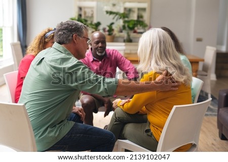 Caucasian senior man consoling crying female during group therapy session. unaltered, support, alternative therapy, community outreach, mental wellbeing and social gathering. Royalty-Free Stock Photo #2139102047