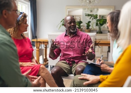 Midsection of multiracial senior males and females discussing during group therapy session. unaltered, support, alternative therapy, community outreach, mental wellbeing and social gathering. Royalty-Free Stock Photo #2139103045