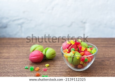 Multicolored cookies in the form of Nuts with filled cream and candied fruit in a glass transparent vase on a wooden table on a light background. Homemade cookies. Copy space. Tasty sweets