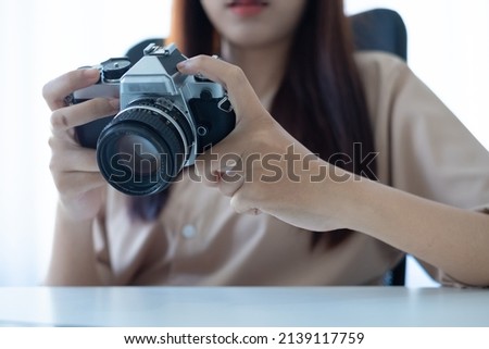 Close-up image, Female hands holding a retro camera over her modern office desk. photographer, blogger, freelancer