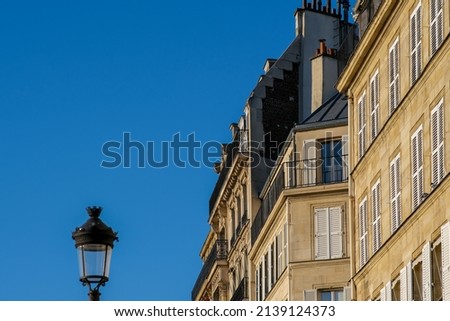 View of a lantern and a typical Parisian residential building with balcony’s and chimneys on a beautiful day in Paris 