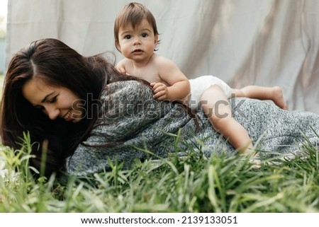  Mother and her son are playing outdoors on a gray background. High quality photo